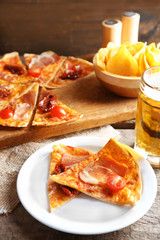 Sliced pizza served with beer on wooden table