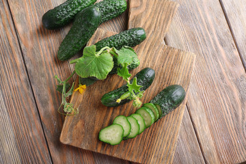 Sliced cucumbers and kitchen board on wooden background