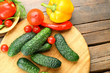 Composition of cucumbers, tomatoes and sweet peppers circles on wooden background