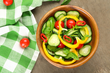 Vegetable salad with cucumbers  on wooden background decorated with green checked cotton serviette and sweet pepper