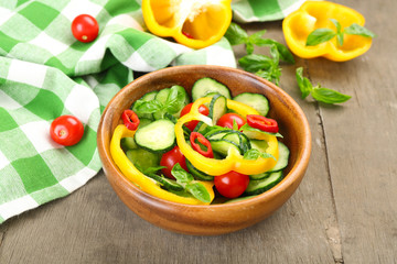 Vegetable salad with cucumbers  on wooden background decorated with green checked cotton serviette and sweet pepper
