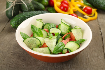 Vegetable salad with cucumbers on wooden background