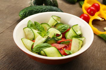 Vegetable salad with cucumbers and pepper on wooden background