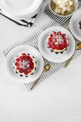 Sweet cakes with raspberries on light wooden background