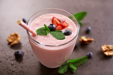 Tasty yogurt decorated with berries, nuts and mint on grey background, close up