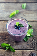 Fresh blueberry yogurt decorated with berries and mint on wooden background