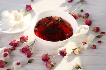 Tea and tea rose flowers on table closeup