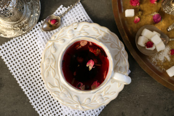 Cup of rose tea with sugar on wooden table