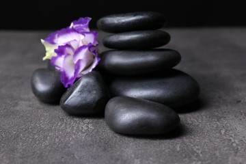 Obraz na płótnie Canvas Balanced pebbles with beautiful flower on dark grey table