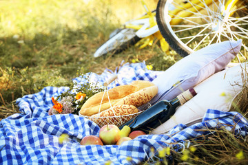 Fototapeta premium Old yellow bicycle and picnic snack on checkered blanket on grass in park