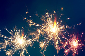 Burning christmas sparkler on blue background
