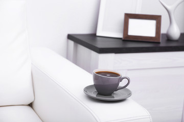 Fototapeta na wymiar Cup of coffee on sofa in room