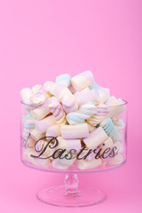 marshmallow candies of different colors in the glass on the background of pink. top view. entertainment for children in celebration.