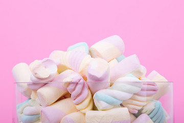 marshmallow candies of different colors in the glass on the background of pink. top view. entertainment for children in celebration.