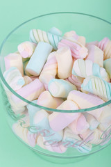 marshmallow candies of different colors in the glass on the background of turquoise. top view. entertainment for children in celebration.