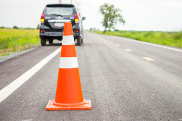 Orange traffic cone on country road. It is used for warning to broken down car on country road, Thailand.