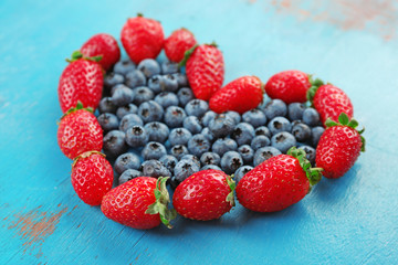 Heart shaped strawberries and blueberries on blue wooden background