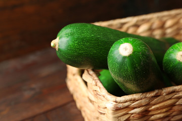 Fresh zucchini in wicker basket on wooden background