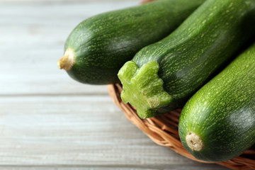 Fresh zucchini on wicker mat on wooden background