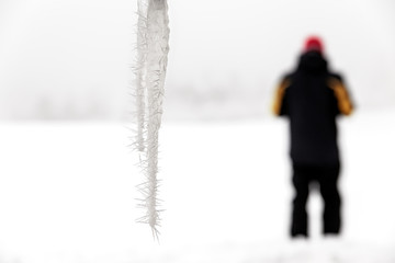 Eiszapfen vor Winterlandschaft mit stehendem Mann