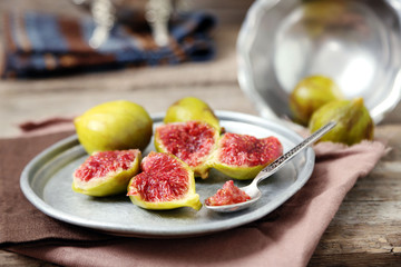 Ripe figs on tray, on wooden background