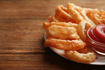 Chips rings with red sauce on plate on wooden background