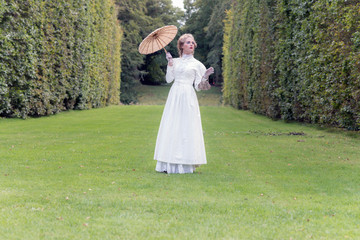 Victorian fashion woman holding parasol standing on lawn with ta © ysbrandcosijn