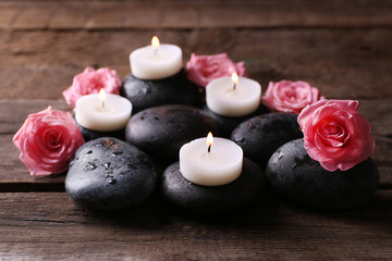 Fototapeta na wymiar Tenderness relaxing composition with pebbles, roses and candles on wooden background