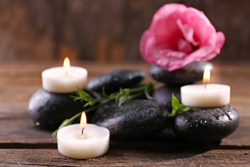 Obraz na płótnie Canvas Alight candles, pebbles and fresh aroma flower composition on wooden background