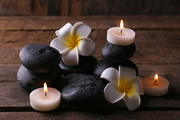 Obraz na płótnie Canvas Relaxing composition with exotic fragipani flower, pebbles and candles on wooden background