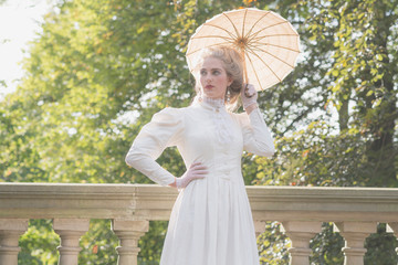 Backlit posh victorian woman with parasol standing on bridge. © ysbrandcosijn