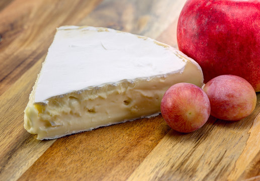Brie cheese with grapes on the wooden background.