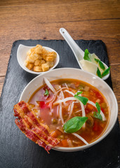 Vegetable soup served with crisp bacon, cheese and croquettes