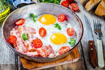 Breakfast with fried eggs, bacon, tomatoes and parsley