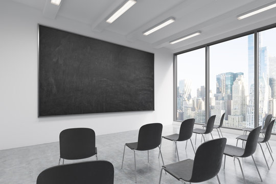 A classroom or presentation room in a modern university or fancy office. Black chairs, a black chalkboard on the wall and panoramic windows with New York view. 3D rendering.
