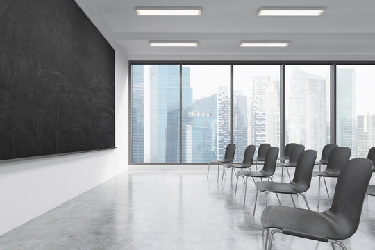 A classroom or presentation room in a modern university or fancy office. Black chairs, a black chalkboard on the wall and panoramic windows with Singapore view. 3D rendering.