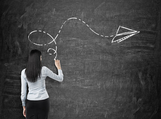 Rear view of brunette in formal clothes who is drawing an arrow as a concept of possible solution...