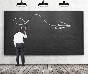 Rear view of a man who is drawing an arrow as a concept of possible solution of the complicated...