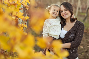 Happy mom with daughter in autumn forest
