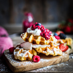 Belgian waffles with fresh berries on rustic wooden background