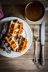 Belgian waffles with chocolate on rustic wooden background