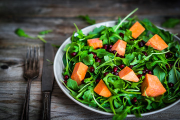 Fresh arugula and spinach salad with pumpkin on rustic backgroun