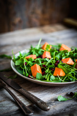 Fresh arugula and spinach salad with pumpkin on rustic backgroun