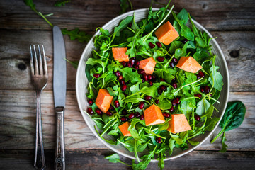 Fresh arugula and spinach salad with pumpkin on rustic backgroun