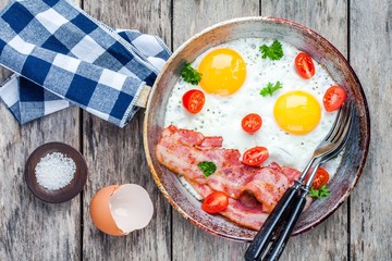 Breakfast with fried eggs, bacon, tomatoes and parsley