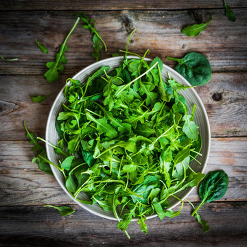 Fresh arugula and spinach salad on rustic background