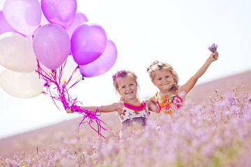 Happy sister are playing with balloons in flower field