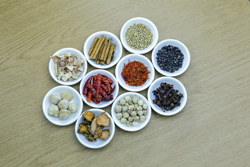 Herbs and spices in white bowls on wooden table