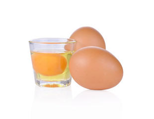 Raw egg in a glass with two eggs on white background