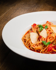 Spaghetti with tomato, parmesan and basil served in a white plate